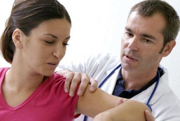 the doctor examines the shoulder joint suffering from osteoarthritis